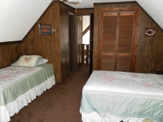 Upper bedroom with two twin beds, half bath and balcony deck.